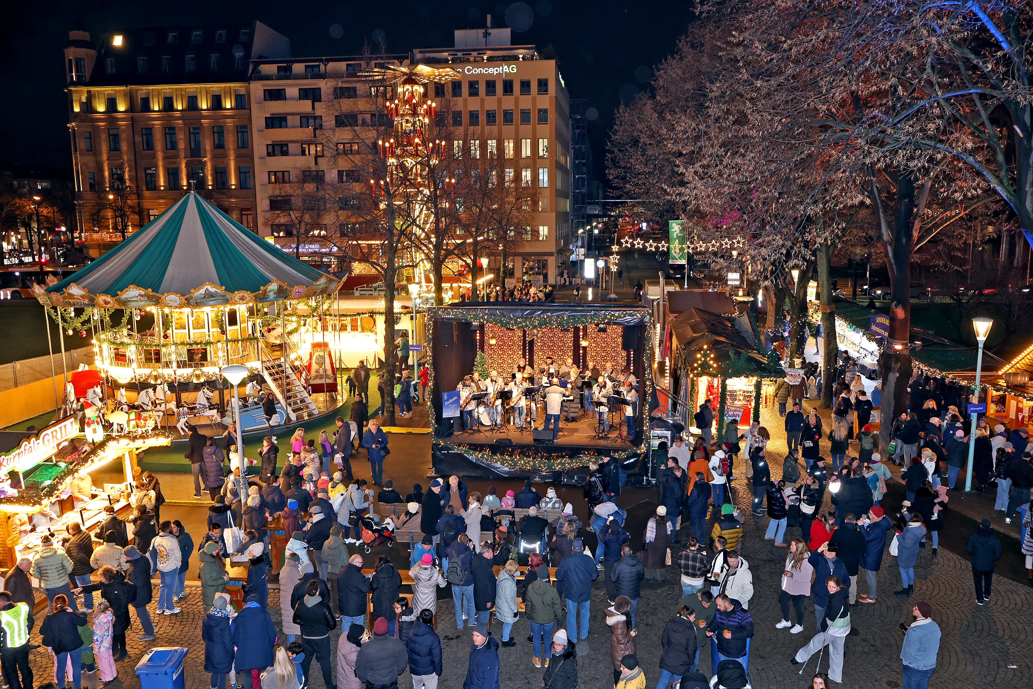 Karussell, Bühne und beleuchtete Stände auf dem Mannheimer Weihnachtsmarkt am Wasserturm. Archivfoto von 2025. Foto: Christoph Blüthner.